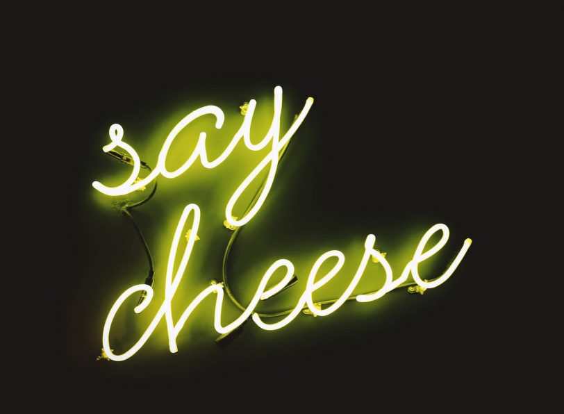 Panneau de néon affichant "Say Cheese", une phrase amusante et familière associée à la pose pour les photos.